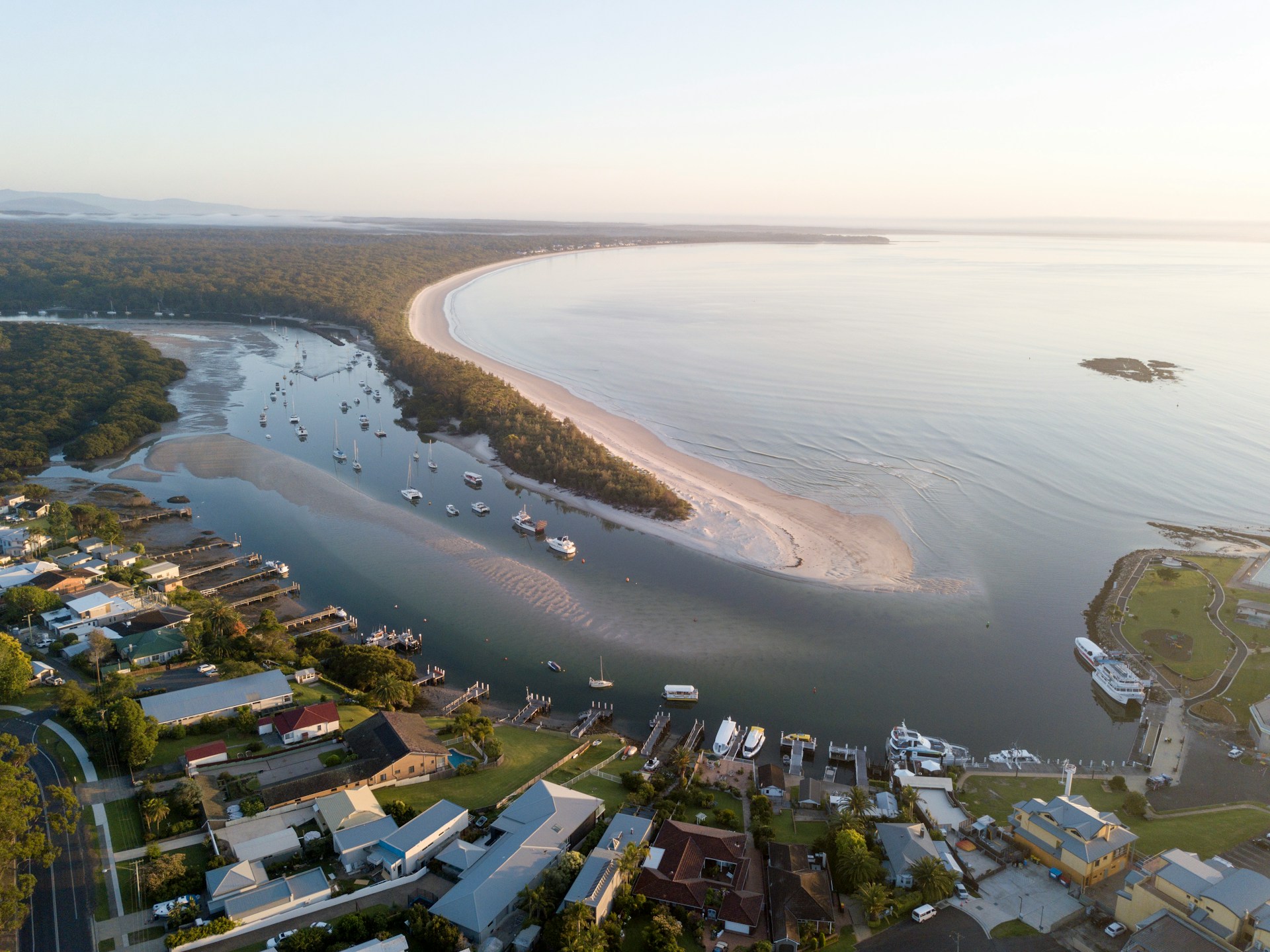 Aerial view of an inlet at Jervis Bay with moored boats and residential streets along the shoreline