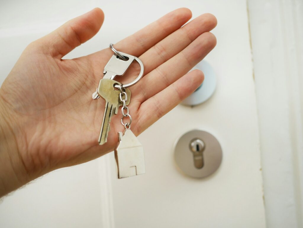 A hand holding house keys at a front door after a successful auction purchase