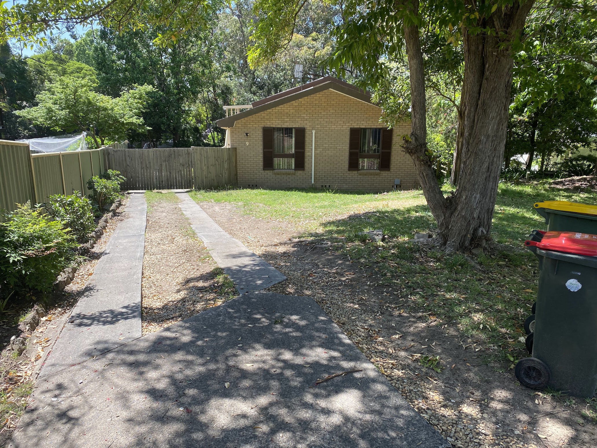A modest brick house with an overgrown front yard, photographed during a midweek inspection